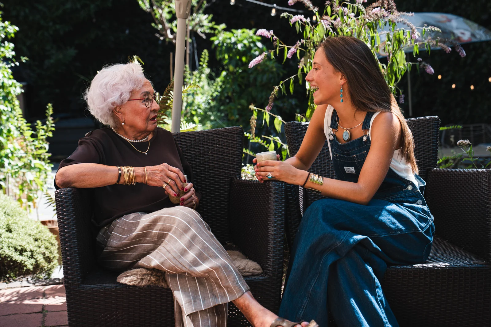 Een jonge aanbieder en een senior vrouw praten ontspannen met elkaar in de tuin